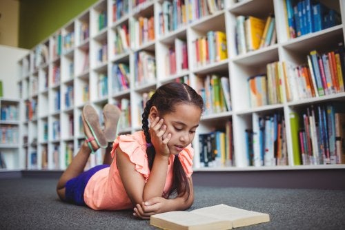 nina con alto nivel educativo lee libro en el suelo de una biblioteca 500x334